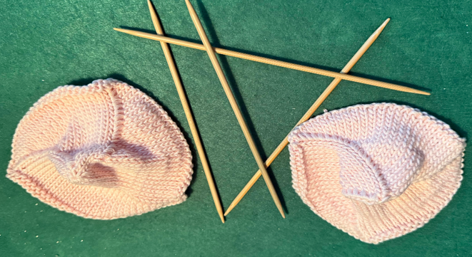 2 finished Knitted Knockers with a set of 4 bamboo double-pointed knitting needles between them