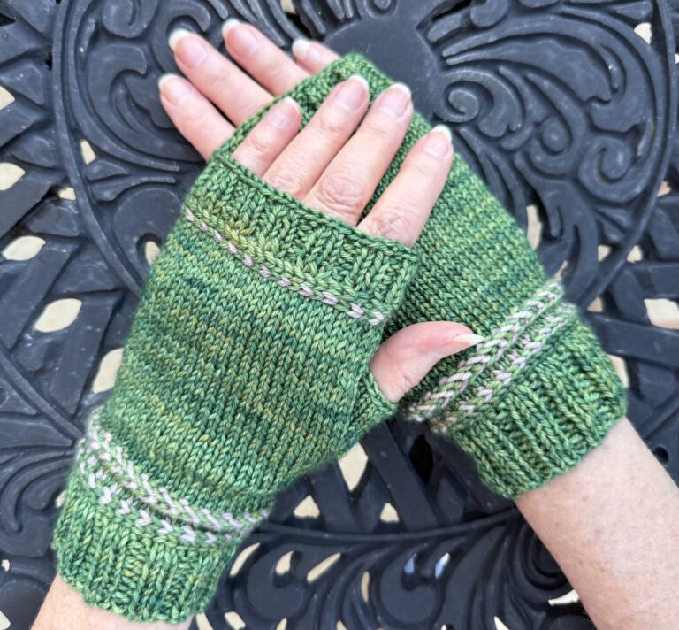 A pair of green knitted fingerless mitts, with braid detailing at the wrist cuff and finger cuffs.